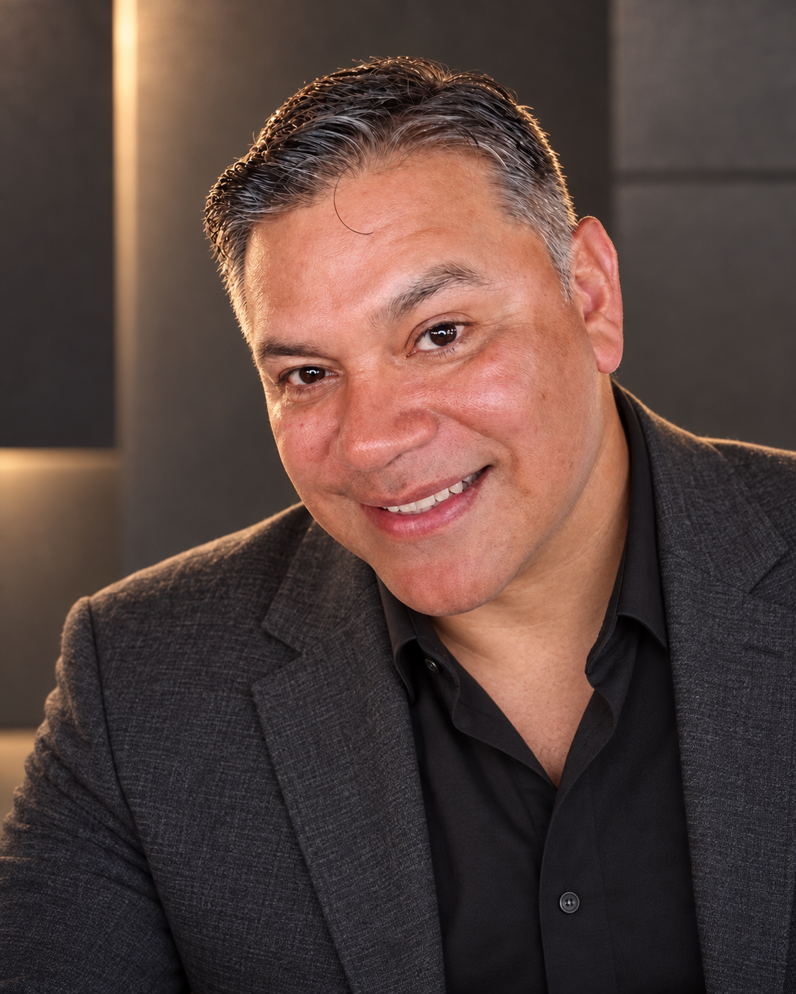 James Esquivel smiling in a charcoal blazer
